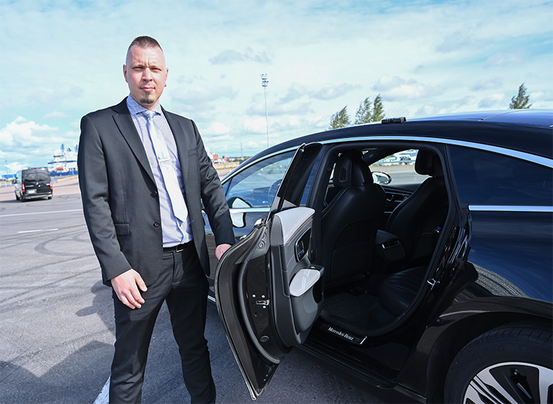taksikuski avaamassa taksin ovea asiakkaalle