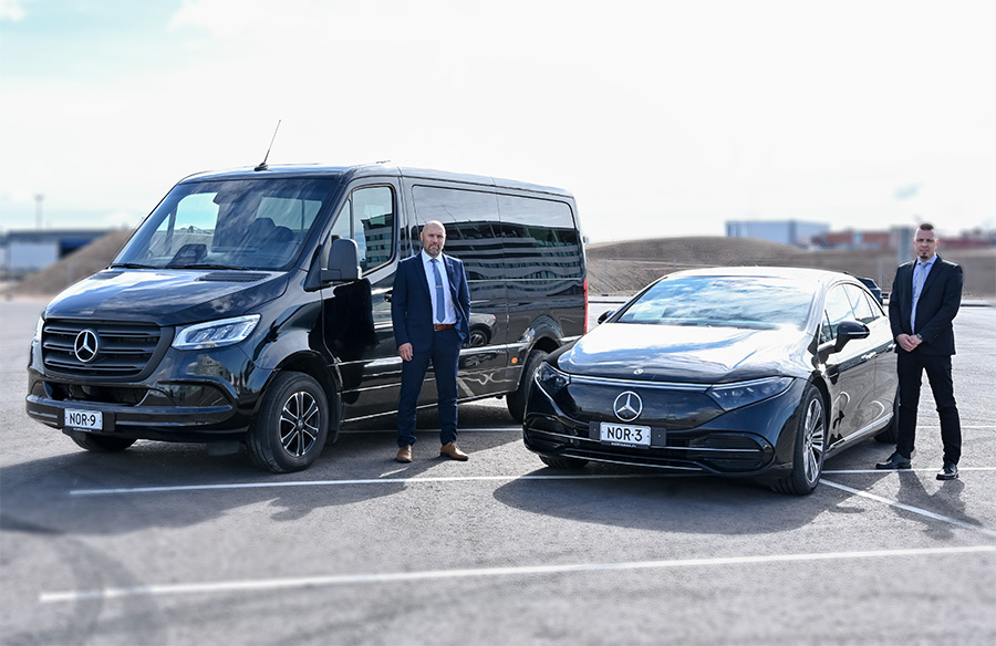 paketti- ja henkilöautotaksit parkkipaikalla, kuskit poseeraa vieressä